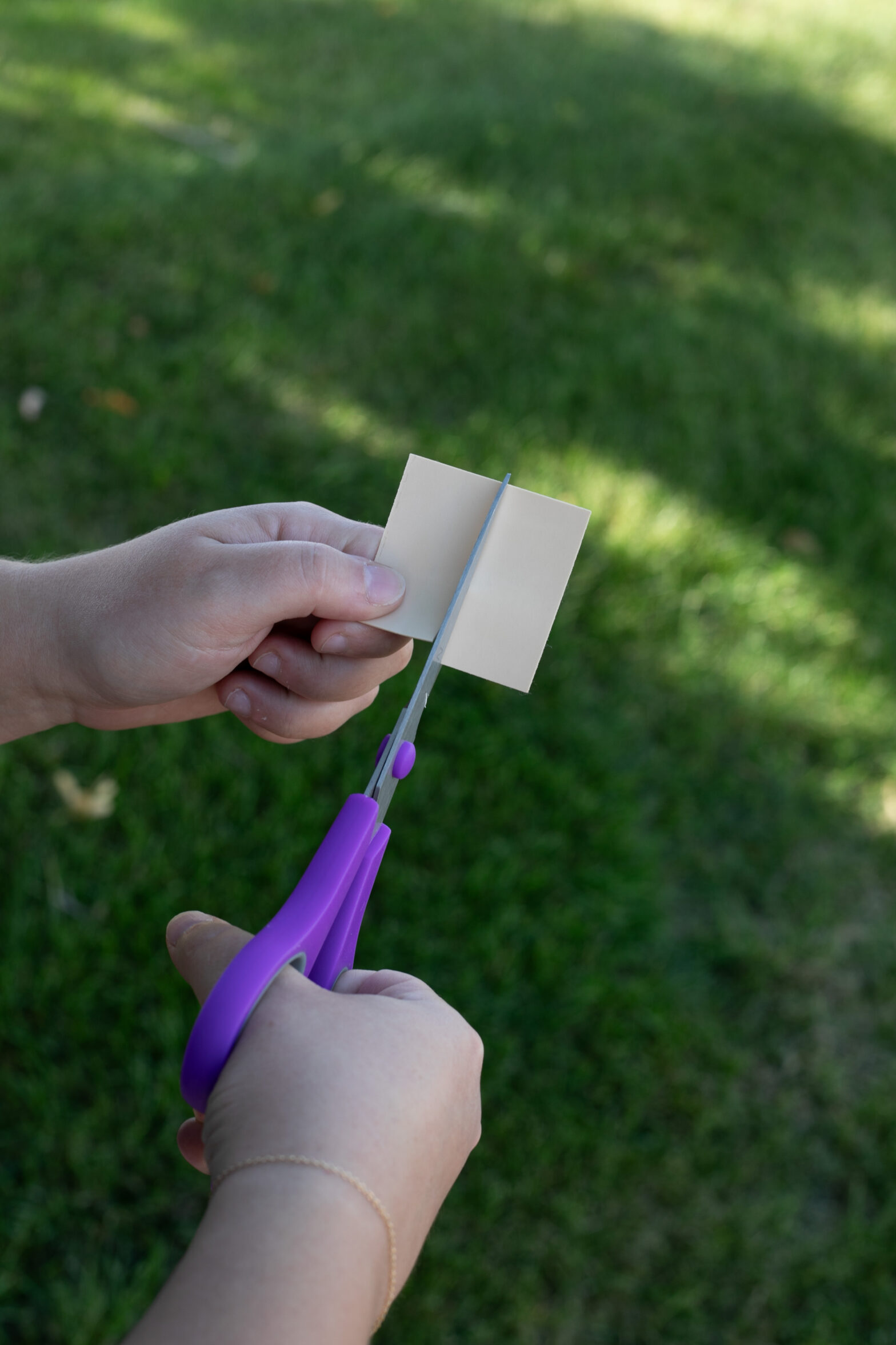 Hand cutting paper with purple scissors