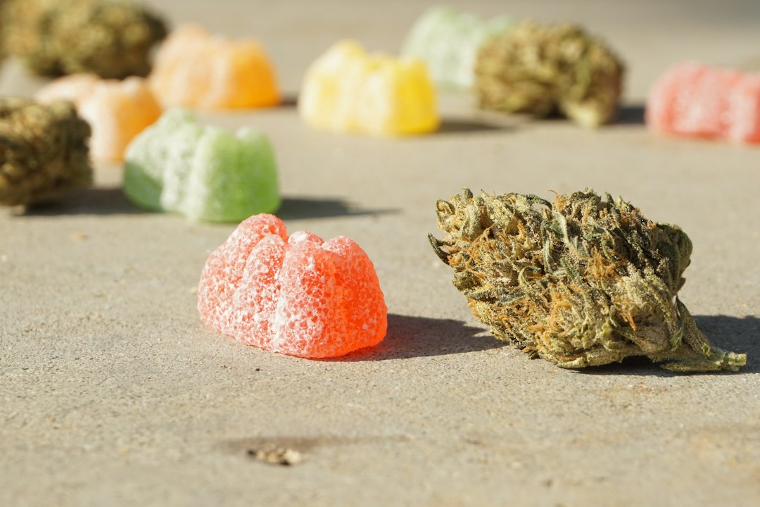 Colorful gummies and cannabis bud on surface