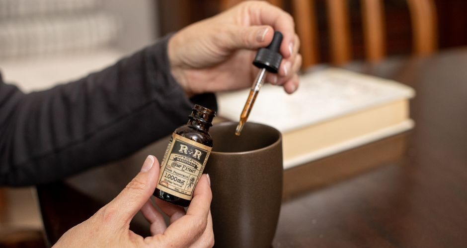 Person adding CBD oil to a mug