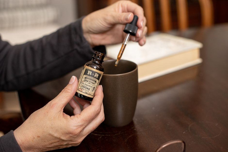 Person adding CBD oil to a mug