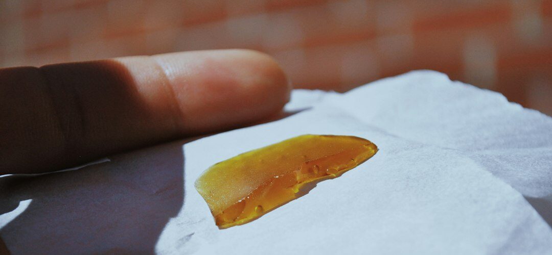 Hand holds translucent amber substance on paper