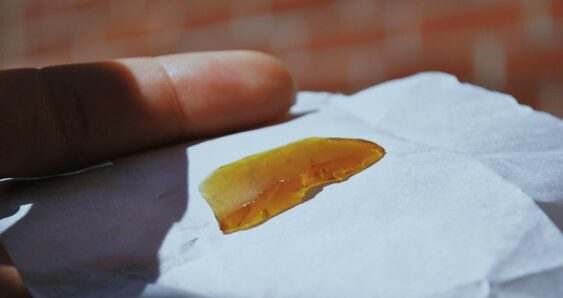 Hand holds translucent amber substance on paper