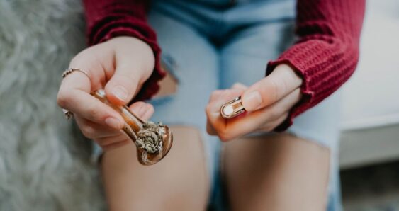 Person holding a glass pipe and lighter