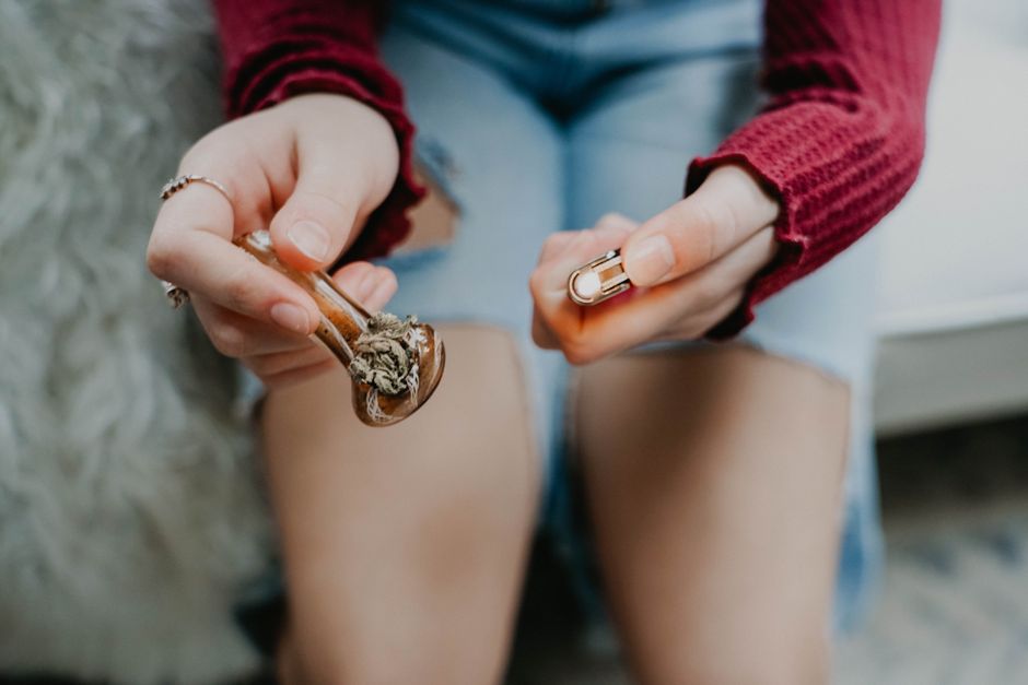 Person holding a glass pipe and lighter